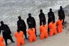 Men in orange jumpsuits purported to be Egyptian Christians held captive by the Islamic State militants kneel in front of armed men along a beach said to be near Tripoli, Libya, in this still image from an undated video made available on social media Feb. 15. The video is said to show the beheading of 21 Egyptian Christians kidnapped in Libya.