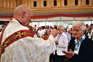 Saskatoon Bishop Mark Hagemoen gives communion to Sr. Brigitta Haag, the oldest of the Ursuline order in Saskatchewan at 100 years old, during a Mass to mark the centennial of the order’s arrival in the province. 
