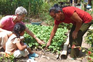 Maryknoll Lay Missioner Peg Vamosy, who has been with the organization since 2008 and served in three countries, is seen with a woman and child at a garden in El Salvador.