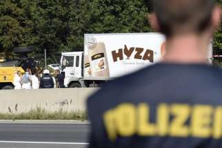 Forensic experts investigate a truck in which refugees were found dead on a freeway between Parndorf and Neusiedl, Austria, Aug. 27.