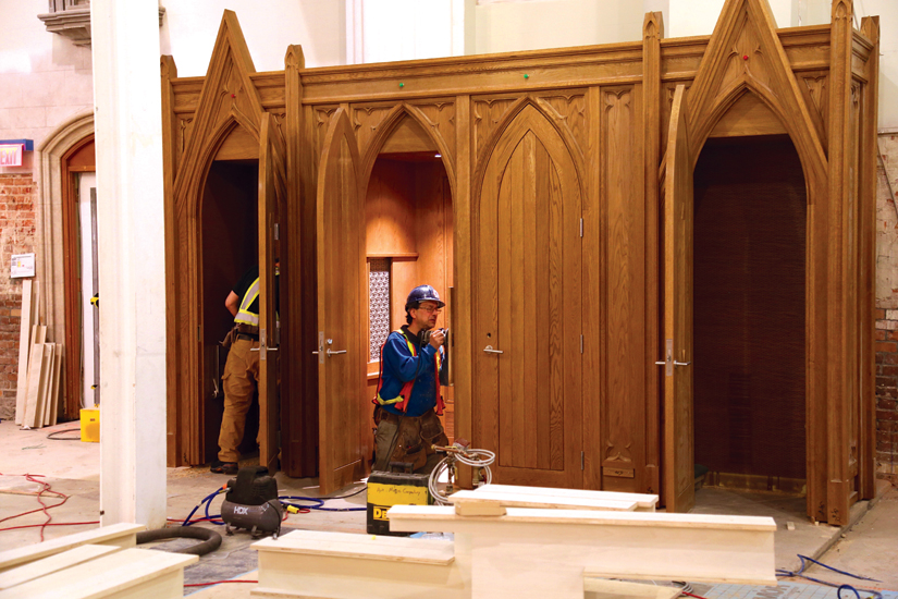 A workman completes the installation of one of the cathedral’s new confessionals. (Photo courtesy of Concrete Pictures Inc.)