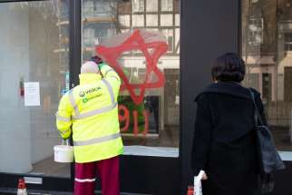 A worker removes anti-Semitic graffiti on a shop window in the Belsize Park neighborhood of London. Cardinal Vincent Nichols of Westminster used his New Year message to condemn the graffiti, saying such hatred &quot;shames us all&quot; and can have no place in society.
