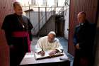  Pope Francis signs a guest book after visiting the Museum of Occupations and Freedom Fights in Vilnius, Lithuania, Sept. 23. At left is Archbishop Gintaras Grusas of Vilnius. 