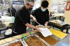 Good Shepherd cooks Matthew (left) and Leigh prepare takeout dinners for an estimated 500 guests.