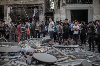 Palestinians look at a destroyed building in Gaza City shortly after an airstrike by Israeli Defense Forces July 17. Caritas Jerusalem officials say Gaza civilians are paying the price for the Israeli-Hamas conflict.