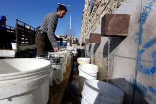 A man fills buckets with drinking water a a public filling area Feb. 3 in Aleppo, Syria. Access to clean drinking water is a basic human right and a key component in protecting human life, Pope Francis said Feb. 24.