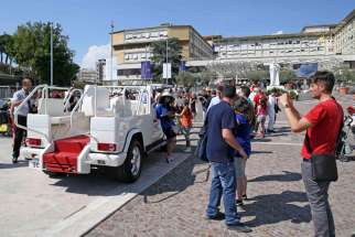 People pose to take pictures with the popemobile in front of Gemelli Hospital in Rome June 27. Pope Francis will ride in a “accessible” popemobile that will not be bulletproof and will have a roof when he visits the Philippines from Jan. 15-19 next year.