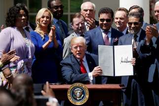 President Donald Trump holds up an executive order he signed during a White House ceremony May 3 to establish a faith-based office, the White House Faith and Opportunity Initiative.