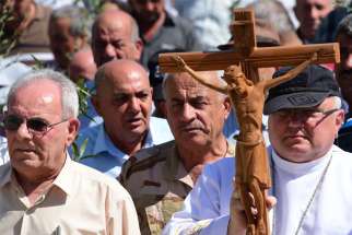 Father Andrzej Halemba is seen in a 2017 file photo carrying a crucifix during a procession of the Christians in Qaraqosh, Iraq.