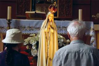 Parishioners pray before the Our Lady of Fatima statue at Canadian Martyrs Church in Toronto.