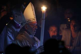 Pope Francis carries a candle as he arrives to celebrate the Easter Vigil in St. Peter&#039;s Basilica at the Vatican April 15.