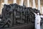 Pope Francis reaches out to the statue titled Angels Unawares by Canadian artist Timothy Schmalz at the Vatican last September. The statue depicts a group of migrants and refugees on a boat. Advocates are urging political leaders to include refugees and migrant workers in aid  support during the COVID-19 crisis.