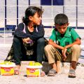 Children sit outside a refugee camp in Kilis, selling fruit to passersby.