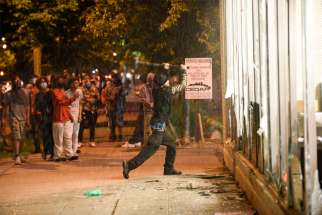 A protester in Minneapolis vandalizes an O&#039;Reilly&#039;s near the Minneapolis Police Third Precinct May 27, 2020. Two days earlier George Floyd, an unarmed black man, was pinned down by a police officer kneeling on his neck before later dying in the hospital May 25.