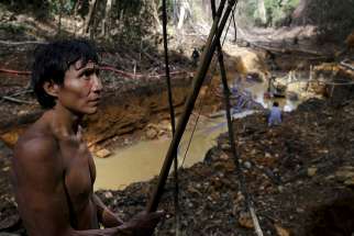 A Yanomami Indian stands near an illegal gold mine during a Brazilian government operation against illegal gold mining on indigenous land in the heart of the Amazon rainforest April 17, 2016.