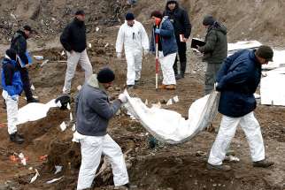 Forensic experts exhume bodies from a mass grave in Kozluk, Bosnia, in this Dec. 15, 2015, file photo.