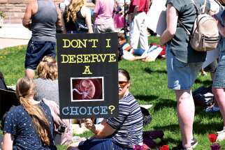A woman hoists a sign at the Toronto March for Life at Queen’s Park May 13.
