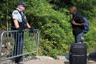 A Haitian man talks with a Royal Canadian Mounted Police officer as he waits to cross the U.S.-Canada border into Quebec in 2017.