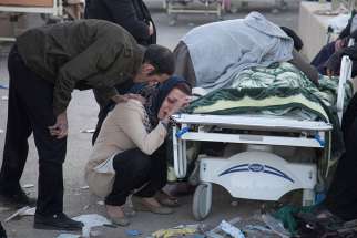 A woman mourns next to a dead body following an earthquake in Sarpol-e Zahab, Iran, Nov. 13. The Nov. 12 earthquake killed more than 400 people and injured more than 6,000 in Iran and Iraq.