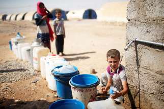 A displaced Iraqi boy fills a bottle with water in Jada, Iraq, Aug. 9, 2017.