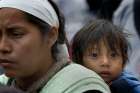 A child looks on as he is carried among Central American migrants walking to the U.S.-Mexico border crossing April 29 in Tijuana, where they presented themselves for asylum.