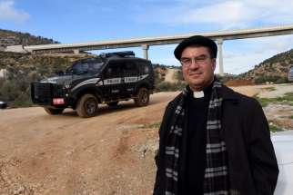 Bishop Oscar Cantu of Las Cruces, N.M., stands in front of an Israeli border police jeep Jan. 10 near the Palestinian land in the Cremisan Valley in Beit Jalla, West Bank.