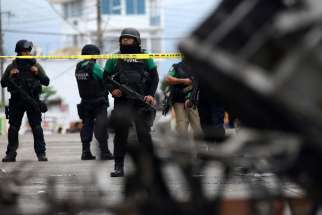  Police officers guard the municipal building in Catemaco, Mexico, Nov. 14 after it was set on fire following the disappearance of Father Jose Luis Sanchez Ruiz, pastor of Twelve Apostles parish . The outspoken priest, who had been reported missing in the state of Veracruz, was found alive, but with signs of torture.
