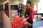 CFS Hamilton staff members Chantelle Pavao and Christine Wong help wrap and organize Christmas gifts for this year’s Miracles on Main Street drive.