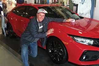 Bob Brehl gets up close with the Honda sports car he won in a raffle at Jays Care.