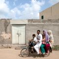 A family rides past the locked house of Rimsha Masih, a Pakistani Christian girl accused of blasphemy, on the outskirts of Islamabad Aug. 23.