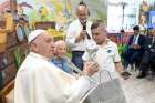 Pope Francis receives a music box shaped like a carousel from a boy named Oscar during a visit to the &quot;Luna Park di Ostia&quot; amusement park in Ostia, Italy, July 31, 2024. Seated next to the pope is Sister Geneviève Jeanningros, 81, a Little Sister of Jesus who lives in a trailer on the carnival grounds and provides pastoral care to the workers.