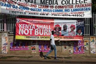 A man walks past a banner calling for prevention of violence during the primary elections April 20 in Kisumu, Kenya. 