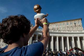 A pilgrim holds up a figurine of the Christ Child as Pope Francis leads the Angelus from the window of his studio overlooking St. Peter&#039;s Square at the Vatican Dec 15, 2019.