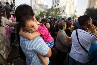 A mother holds her sick daughter in Manila, Philippines, Jan. 19, while waiting for Pope Francis to commute to the airport and return to Rome. 