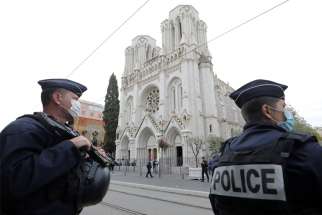 Police stand near Notre Dame Basilica in Nice, France, Oct. 29, 2020, after at least three people were killed in a series of stabbings before Mass. France raised its alert level to maximum after the attack.