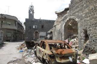 A destroyed car is seen outside a school in Homs, Syria. Two car bombs exploded near the school Oct. 1, killing at least 47 school children. On a visit to Canada, Jesuit Father Ziad Hilal, working with Jesuit Refugee Service in Syria, urged caution and c alled for renewed efforts to find peace.