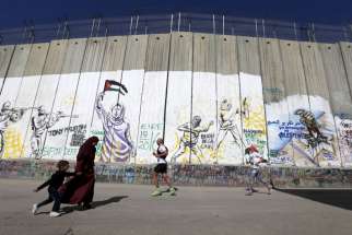 Participants run past the controversial Israeli separation barrier during the annual Right to Movement Palestine Marathon in Bethlehem, West Bank, April 1.