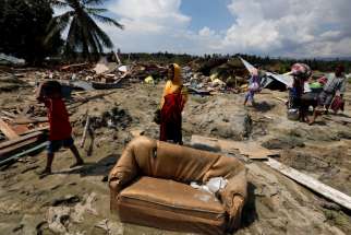 Villagers carry their belongings as they walk through mud near the ruins of houses after an earthquake hit Indonesia’s Sulawesi island. 