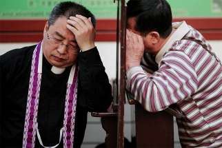 A priest hears confession on Holy Thursday, March 29, at the Cathedral of the Immaculate Conception in Beijing. For the first time in decades, all of the Catholic bishops in China are in full communion with the Pope, the Vatican announced Sept. 22. 