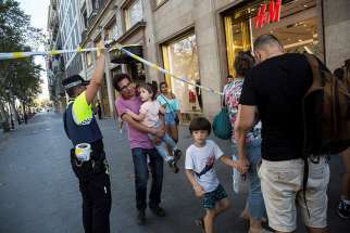 A police officer helps evacuate people after a van crashed into pedestrians in the Las Ramblas district of Barcelona, Spain, Aug. 17. Terrorists killed at least 12 and injured more than 50 others.