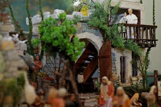 A tiny statue of Pope Francis is seen waving from a balcony on a miniature Nativity scene depicting a Middle Eastern village set inside the Holy See press office Dec. 19 at the Vatican. 