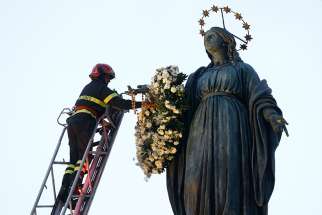  A firefighter places a wreath on a tall statue of Mary overlooking the Spanish Steps in Rome Dec. 8, the feast of the Immaculate Conception. Rome&#039;s firefighters have observed the tradition every year since 1857. 