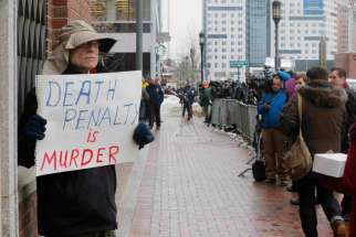 A man holds a sign reading &quot;Death penalty is murder&quot; March 4 outside the trial of accused Boston Marathon bomber Dzhokhar Tsarnaev in Boston. Four nationally circulated Catholic publications called for abolishing the death penalty in the United States in a jointly published editorial March 5. 