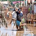 A resident carries chairs he salvaged from his damaged shanty.