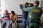 A U.S. Border Patrol agent applies handcuffs to people suspected of crossing the Rio Grande River illegally near McAllen, Texas, Feb. 28.