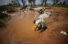 A woman collects water for washing as floodwaters begin to recede in the aftermath of a 2019 cyclone near Beira, Mozambique. Many climate scientists have associated an increased number of natural disasters and their severity with climate change.