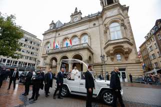 Pope Francis greets people gathered on the streets of Luxembourg to see him pass by in the popemobile Sept. 26, 2024.