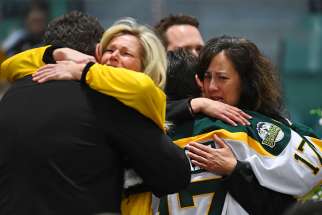Mourners embrace during an April 8, 2018 vigil at Elgar Petersen Arena in Humboldt, Saskatchewan, to honour members of the Humboldt Broncos junior hockey team who were killed in a fatal bus accident. 