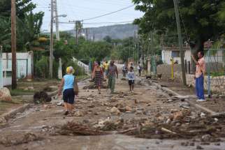 People walk on the street after strong waves hit the coast Oct. 4 near Santiago de Cuba ahead of the arrival of Hurricane Matthew.