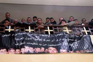 Neighbors and friends of the relatives of Egyptian men said to be killed in Libya attend Mass at a church south of Cairo Feb. 16 and pray in front of a banner with pictures of the victims. Egyptian jets bombed Islamic State targets in Libya Feb. 16, a day after the group there released a video showing what is said to be the beheading of 21 Egyptian Christians.